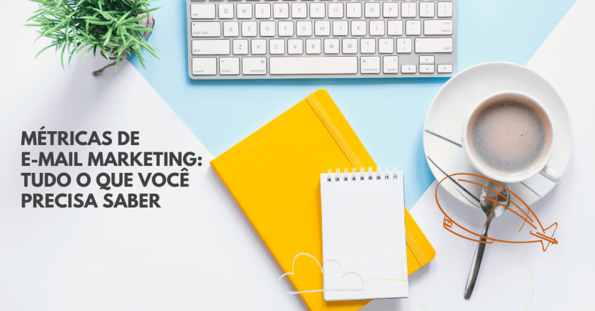Foto de uma mesa vista de cima. Em cima dela há um teclado de computador, um caderno amarelo e uma xícara de café. No lado esquerdo está o título do post: Métricas de e-mail marketing: o que você precisa saber